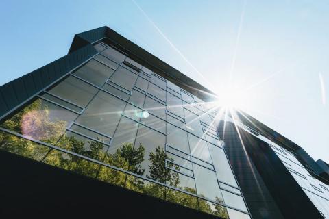 Light shining off a modern building with trees visible in the reflection